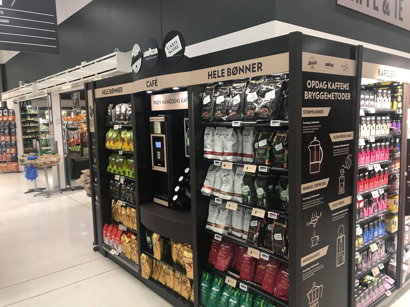 Kaffesalgsdisplay med forskellige kaffebønner og en kaffemaskine i en butik.