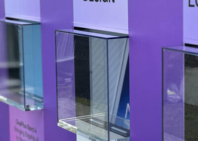 Gennemsigtig kasse til indsamling af forslag, placeret på en lila baggrund med teksten 'DESIGN'.