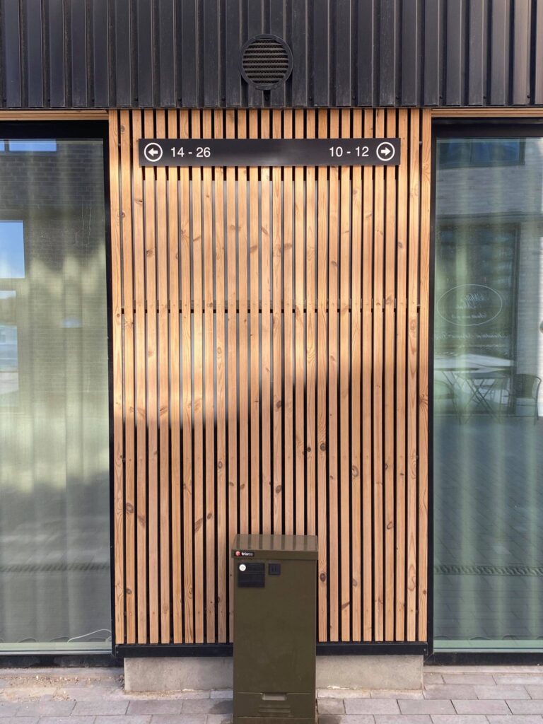 Facade med træbeklædning og nummereringsskilt til bygninger 14-26 og 10-12.