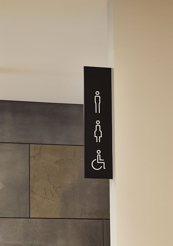 Skilt med symboler for herretoilet, dametoilet og handicaptoilet i moderne design.