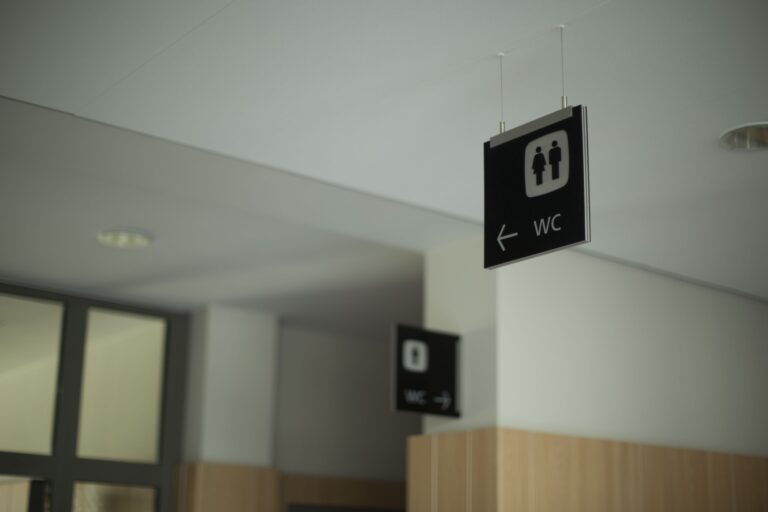 Skilt der angiver retningen til toiletter med symboler for mænd og kvinder.