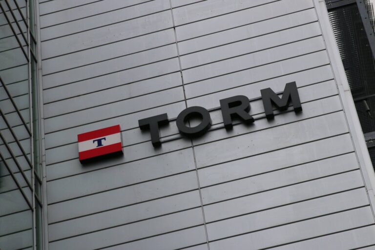 Skilt med navnet TORM på en bygning, præsenteret med en rød og hvid flaggrafik ved siden af.