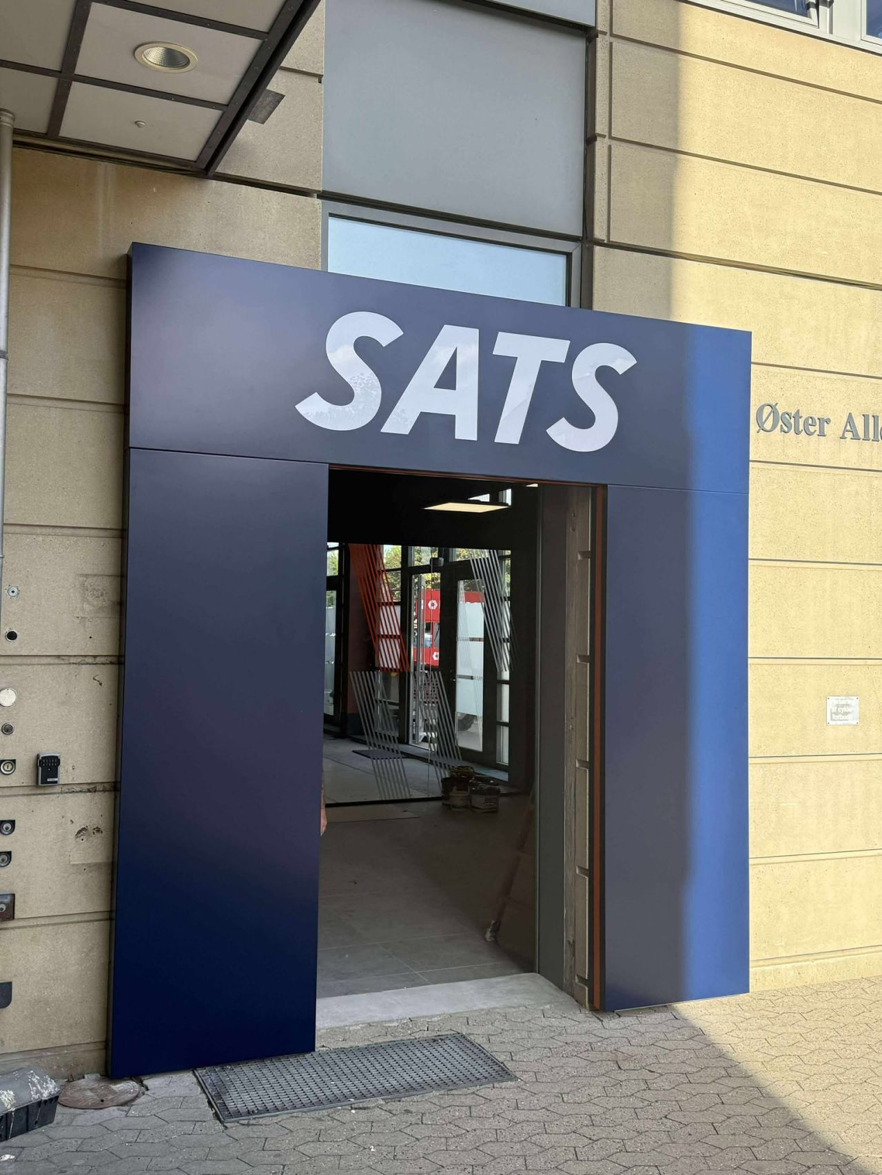 Vægkunst med et stort, blåt 'S' på en stribet baggrund i en indendørs indstilling.