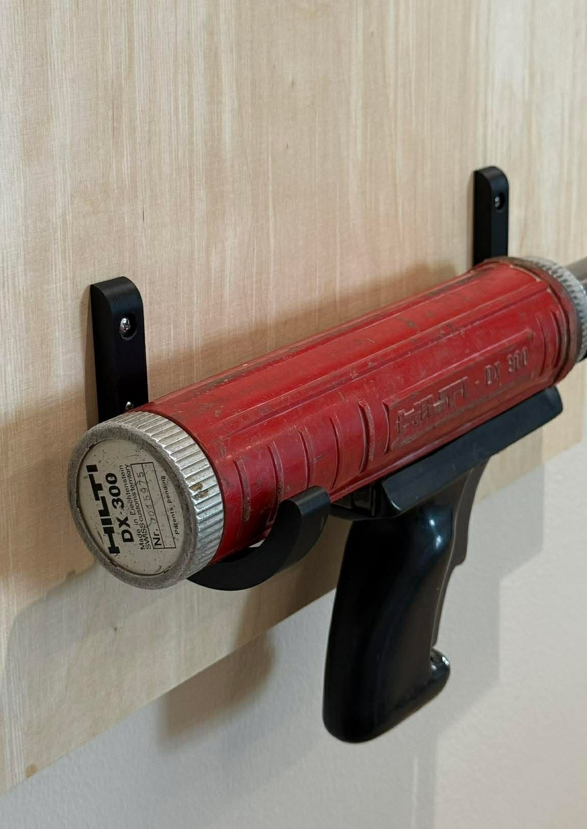 Hilti DX 300 monteringsværktøj er fastgjort på en lys træplade med sorte beslag og håndtag, mens den røde enhed bruges til præcis opsætning.