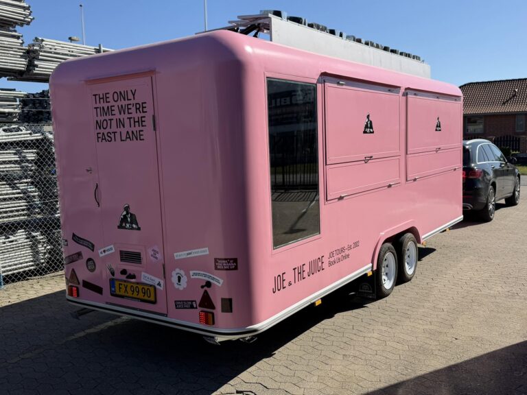 Den pink Joe & The Juice foodtruck står med tydelig branding, citat på bagdøren og flere salgslemme, klar til servering på pladsen.